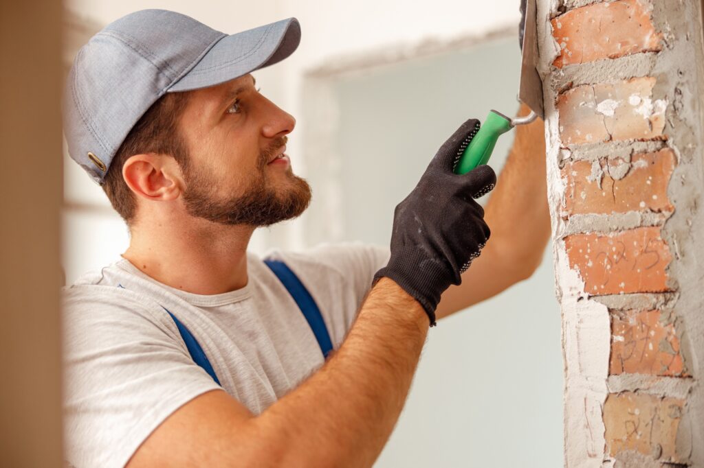 Portrait of smiling handyman or craftsman filling the wall, preparing it for painting
