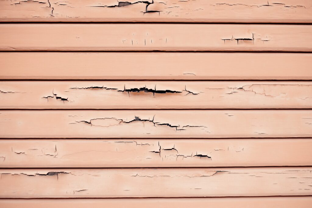 Siding Repair 5 Textured wainscoting wall paneling with chipped and cracked paint chips falling off.
