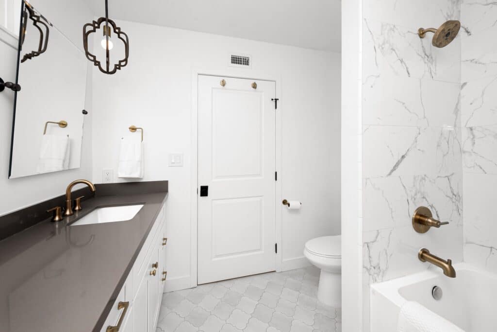 White bathroom with black counter and marble floors